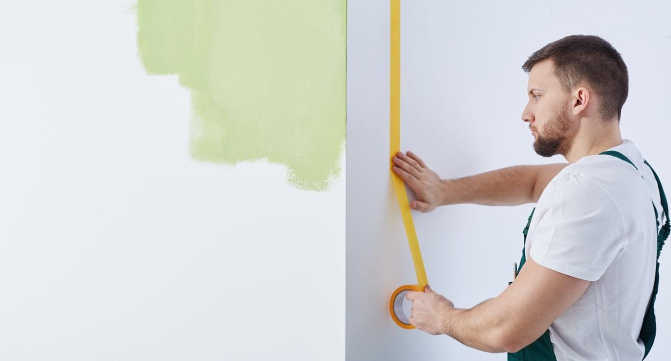 Man is sticking adhesive tape into the wall