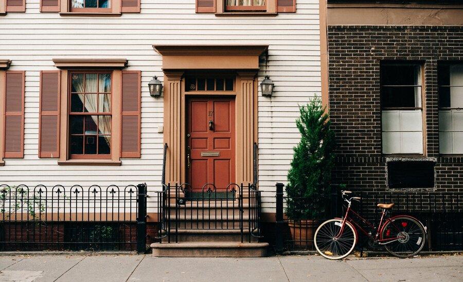 Red bicycle parked beside a black metal gate in front of a house