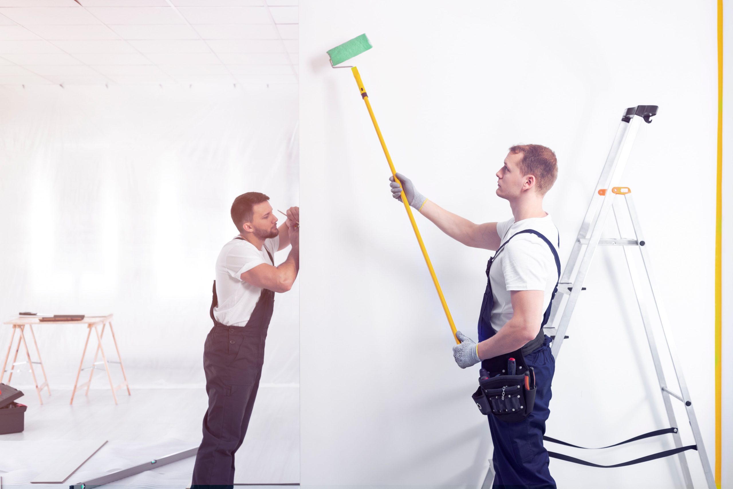 decorators painting a wall with a roller during renovation