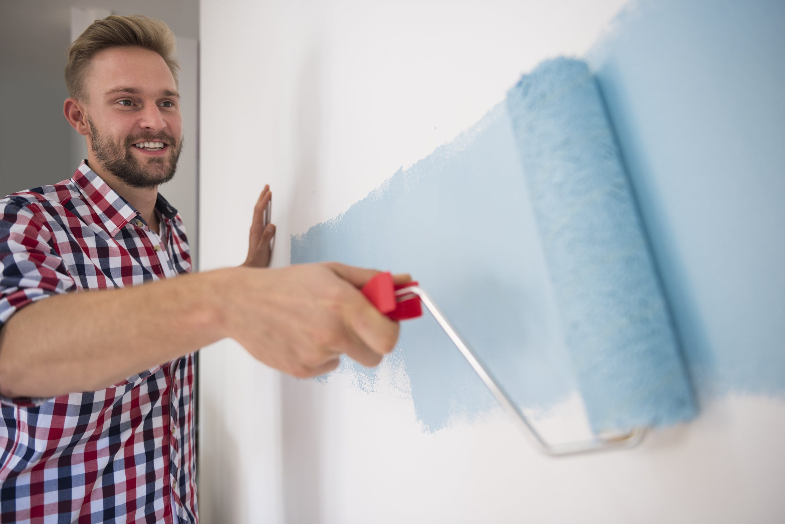 young man painting blue wall