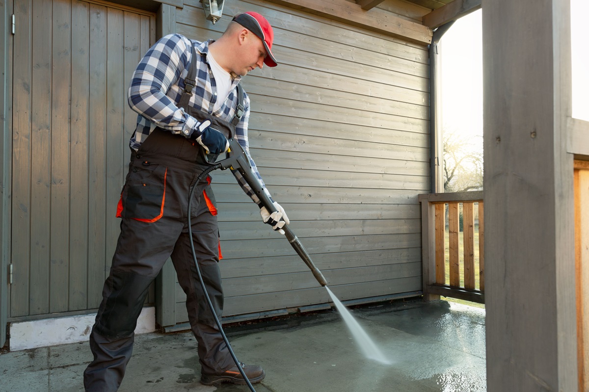 man is cleaning terrace with pressure cleaner