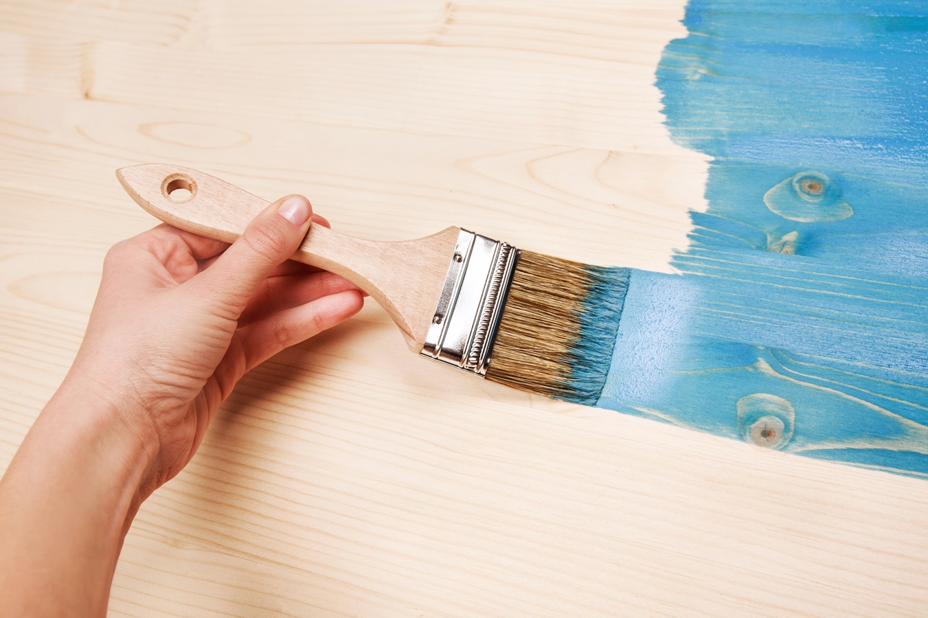 hand painting blue colour on wooden table
