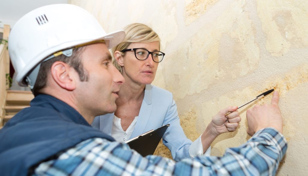 Builder points at wall while supervisor looks