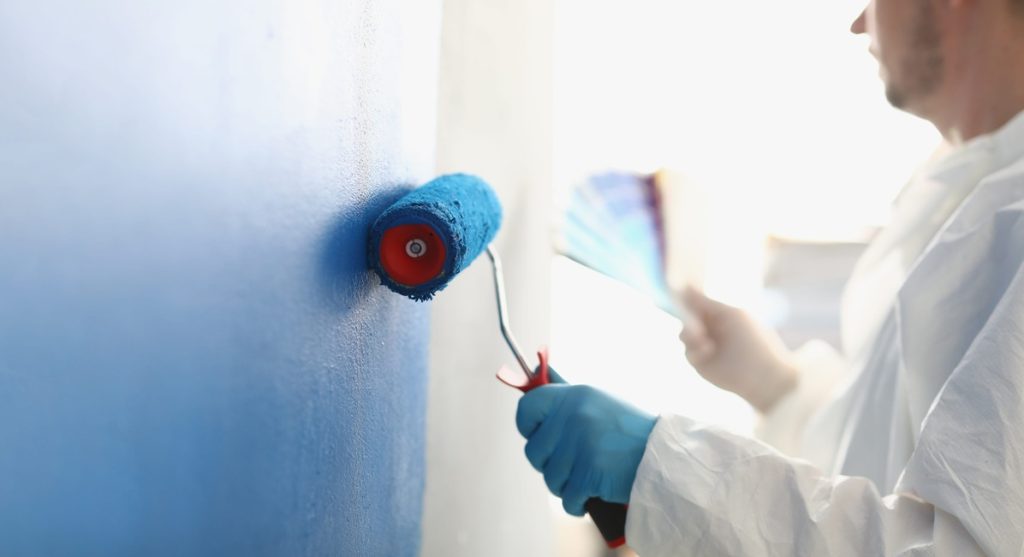 painting white wall with blue roller